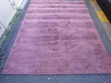 purple area rug on the ground next to a car parked on the side of the road