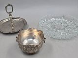 deux plats en métal argenté et un saladier en verre posés sur une table