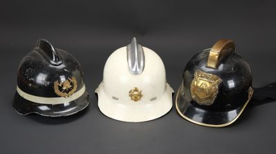 trois casques de pompier sont alignés sur une surface noire