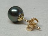 une perle noire et une boucle d'oreille en or sur un fond blanc