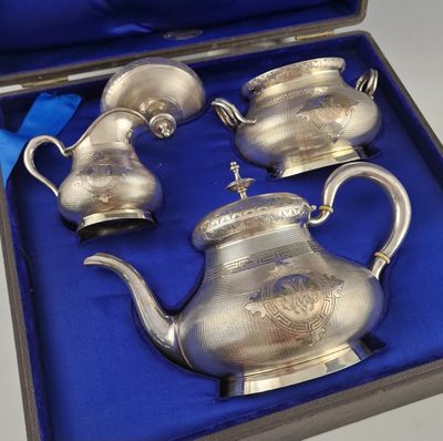 three silver teapots in a blue box on a table