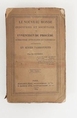 un vieux livre posé sur une table à côté d'un mur blanc