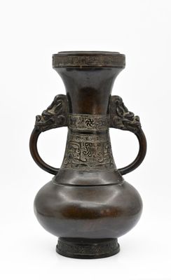 un vase en bronze muni d'une anse, sur fond blanc