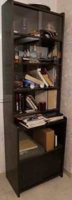 une bibliothèque noire sur laquelle sont posés des livres, dans une pièce