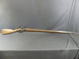 Un vieux fusil est posé sur une table recouverte d'un tissu gris.