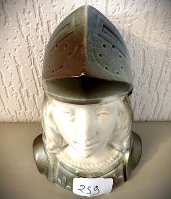 une figurine en céramique représentant une femme portant un casque, posée sur une table