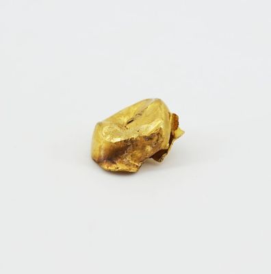 a close up of a piece of gold on a white surface