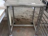 a table with a metal frame on wheels in a room