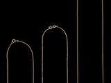 trois colliers en or et deux colliers en argent sur fond noir