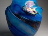 un vase bleu orné d'un motif en spirale, posé sur une surface grise