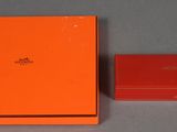 une boîte orange et une boîte rouge posées sur une surface grise