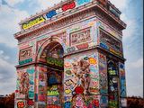 a large arch covered in graffiti on the side of the road
