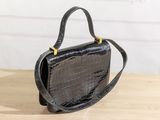 a black crocodile skin handbag on a wooden table