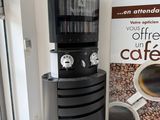 a coffee machine sitting next to a coffee cup dispenser