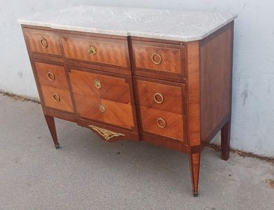 une commode au plateau en marbre posée sur le trottoir