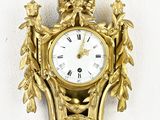 une horloge dorée accrochée au mur, avec un mur blanc en arrière-plan