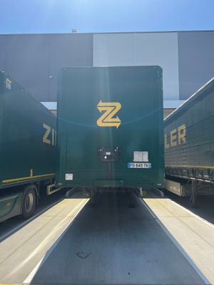 two green semi trucks parked next to each other in a parking lot