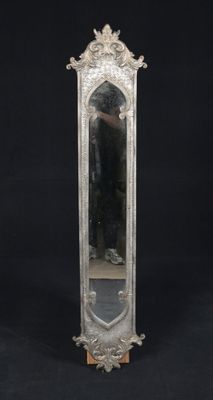 an ornate silver mirror with a wooden stand on a black background