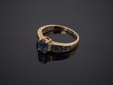a gold ring with blue sapphires and diamonds on a black surface