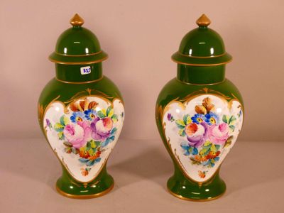 two green vases with flowers on them on a table