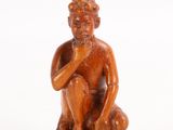 an old wooden statue of a man sitting on top of a wooden stump