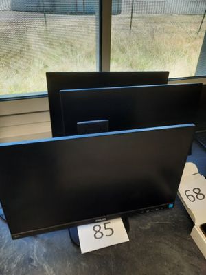 trois écrans d'ordinateur posés sur une table devant une fenêtre