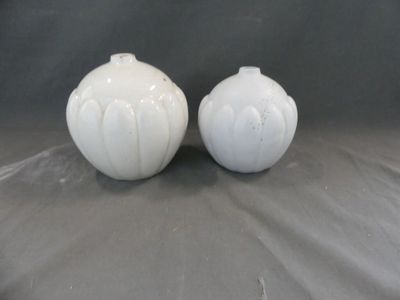 deux vases blancs posés l'un à côté de l'autre sur une table