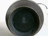 a black vase sitting on a white surface with a light in the background