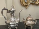 deux théières en argent posées sur une table à côté d'un miroir