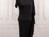 une robe noire posée sur un mannequin devant un mur blanc