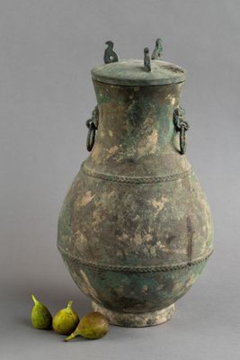 un grand vase vert surmonté de deux figurines