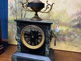 une horloge posée sur une table à côté d'un tableau