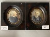 two framed portraits of two men, one with a beard and the other with a mustache