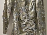 une robe argentée suspendue à un cintre contre un mur