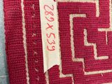 a close up of a red and white rug with a tag on it