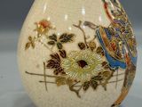 a white vase with a bird and flowers on it
