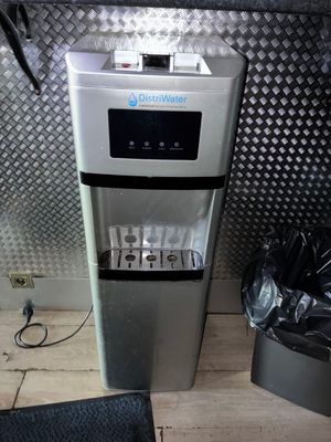 un distributeur d'eau posé par terre à côté d'une poubelle