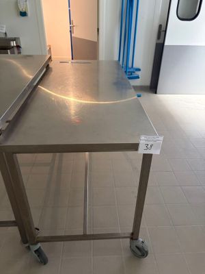 une table en acier inoxydable sur laquelle est posé un ordinateur portable