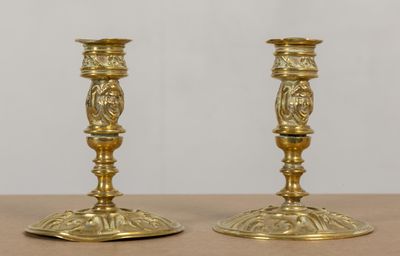 une paire de bougeoirs anciens en laiton posés sur une table en bois