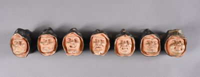 six ceramic heads of a man and a woman on a gray surface