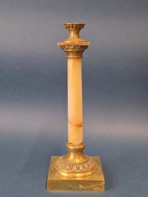 un bougeoir ancien en laiton avec un socle en marbre, sur fond bleu