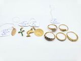 several gold rings and other jewelry on a white surface