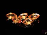 three orange topazte gems on a black surface