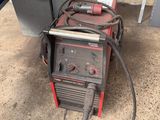 an image of a welding machine sitting on the ground next to a refrigerator