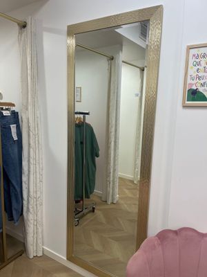 une chaise rose devant un miroir dans une pièce