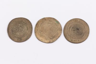 three old coins sitting side by side on a white surface