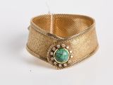 un gros plan d'un bracelet en or orné d'une pierre turquoise
