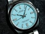 a rolex watch with a blue dial on a black surface