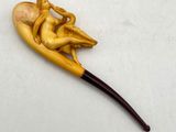 a small wooden pipe with a figurine sitting on top of it
