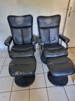 une paire de fauteuils inclinables en cuir noir, avec repose-pieds et pouf assortis